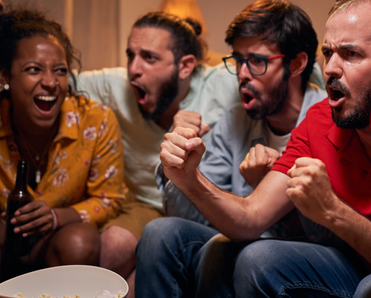 A group of friends are cheering and watching a game on TV.
