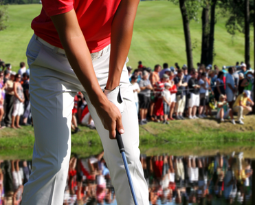 A crowd watches a golfer as they take a swing.