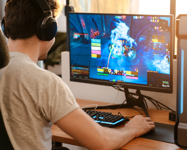 A man wears headphones and plays a game on his PC. 