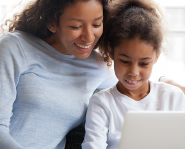 A mom and daughter sit together using a laptop.