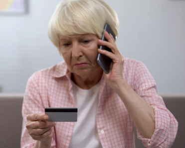 Senior lady looks upset on the phone as she looks at her credit card