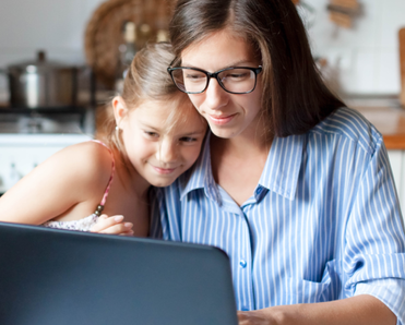 A mom and daughter use the computer together.