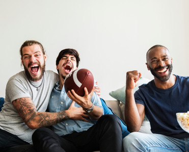 Three men cheer for their football team while watching a game at home.