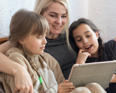 A mom and her two kids use an iPad together.