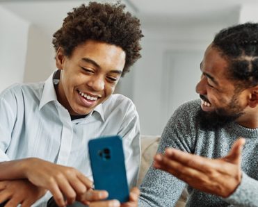 A father shows a phone to his son. 
