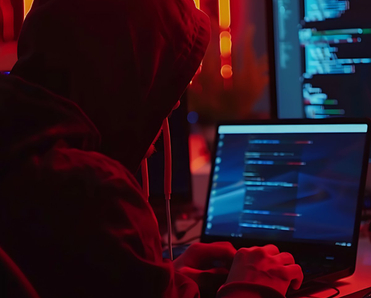 Hacker leaning over laptops