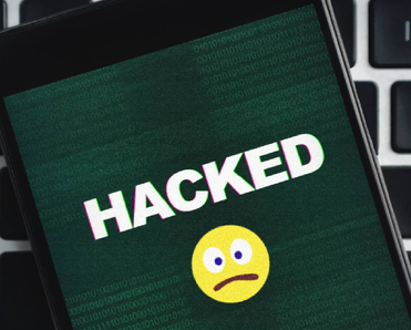 Closeup of a smartphone with a sad emoji and the word Hacked in all caps