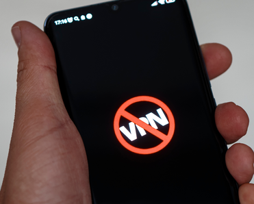 Man holding phone that shows the word "VPN" crossed out because it's been banned.