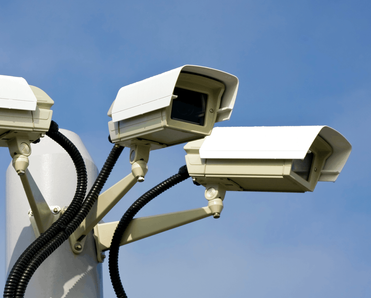 Three surveillance cameras on an outdoor post.