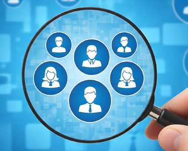 A hand holding a magnifying glass over blue digital user profiles