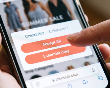 Hand holding smartphone with cookie policy consent popup on screen