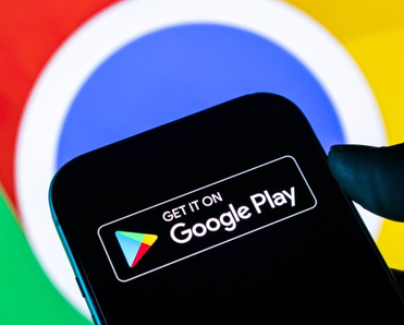Closeup of a hand holding a smartphone displaying the Google Play Store logo against a Google Chrome background.