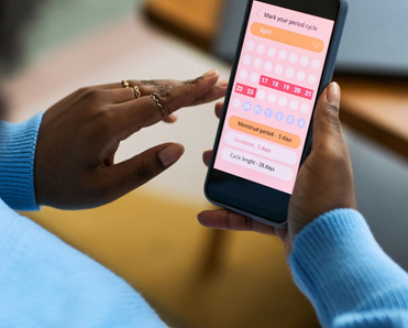 Woman using smartphone to track menstrual cycle.