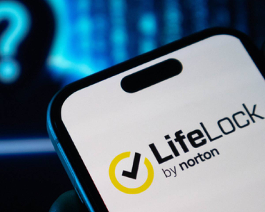 Closeup of LifeLock by Norton logo on smartphone with shady hacker figure in background