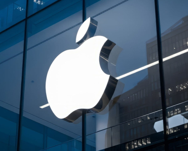 The Apple logo is prominently displayed on the exterior of a modern glass building.
