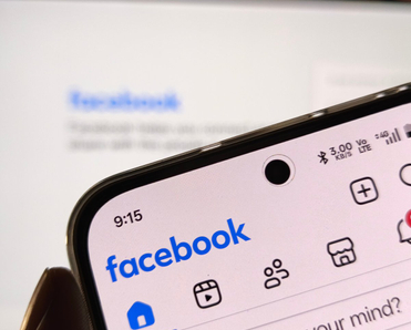 Smartphone showing facebook application interface on a blurred background.