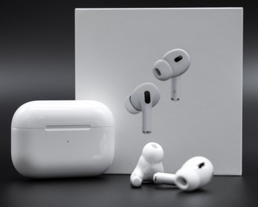 Apple AirPods Pro 2nd generation next to charging case and packaging box on black background.