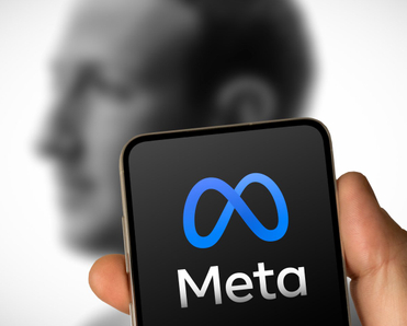 Phone with Meta logo on it in front of faded picture of Mark Zuckerberg.