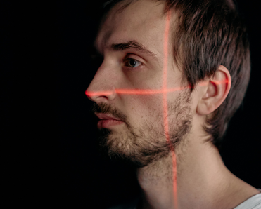 A man with a red crosshair laser over his face.