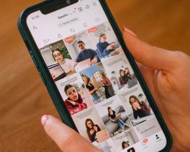 A well-manicured pair of hands holds a phone open to TikTok.