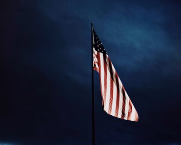 A drooping American flag amid a dark sky.