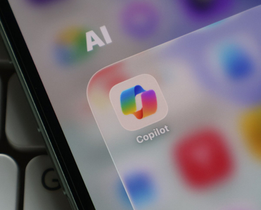 Closeup of a smartphone screen displaying the Microsoft Copilot app icon inside an AI folder.