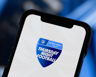 A closeup of a smartphone displaying Prime Video icon with text 'Thursday Night Football'