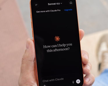 Hand holding cell phone with a new Claude chat opened on the screen.