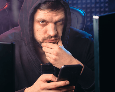 A man rubs his chin as he browses his phone.