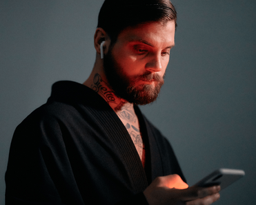 Bearded man in red lighting using a smartphone.