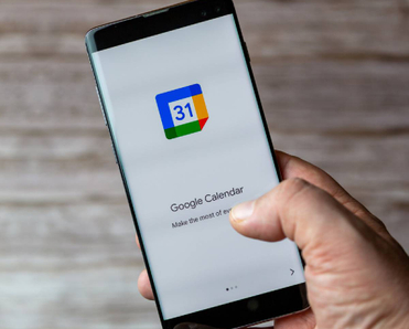 A Mobile phone or cell phone being held showing the Google Calendar app open on screen