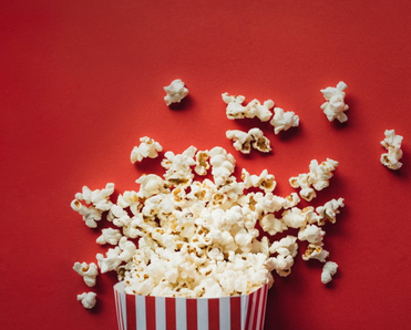 A box of popcorn laying on the red ground.