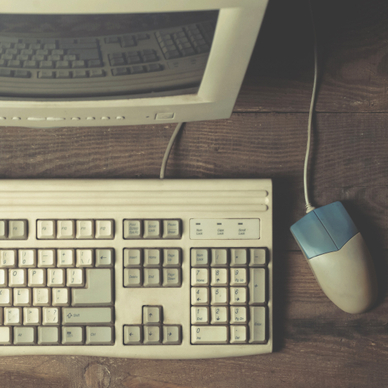 A top-down photo of a vintage computer with a boxy CRT monitor, beige keyboard, and wired mouse