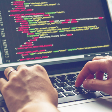 A pair of hands types on a laptop keyboard while the screen shows several lines of HTML code used to create a web page