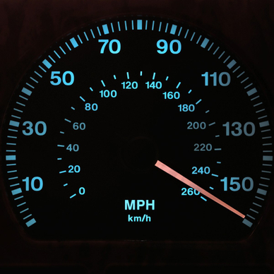 A close-up shot of a lit-up speedometer on a car&#x27;s dashboard. The needle is sitting at just over 150 miles per hour to show fast speeds.