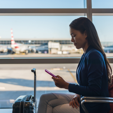 A woman uses her cell phone on public Wi-Fi while waiting to board a flight at the airport.