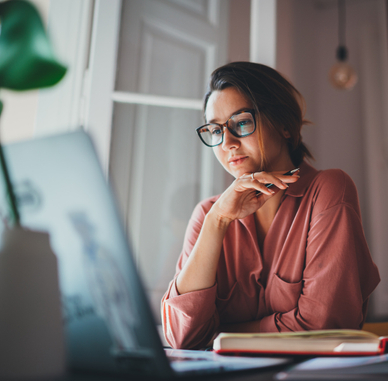 A woman sits at her desk and looks at her laptop. If she&#x27;s using public Wi-Fi, she should check to make sure her VPN is working.