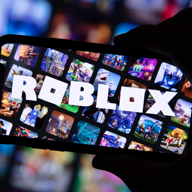 Cellphone held my hand in the dark, screen with many squares game images and the word ROBLOX across
