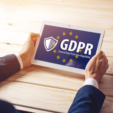 Two hands are holding a tablet with a screen on the GDPR and the EU flag in the background.