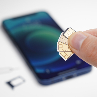 fingers holding several sim cards blurry phone in the back
