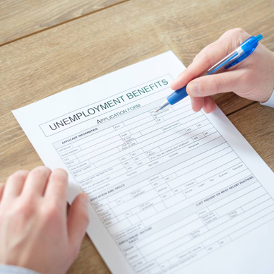 A close-up of someone filing an unemployment benefits application form in pen.