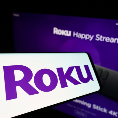 Roku purple logo on phone screen and in the back on TV 