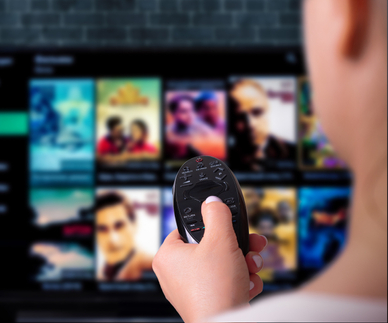 A woman clicks through different shows on a TV