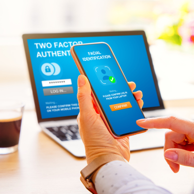 Phone and laptop in the background with blue screen and two-factor authentication lock