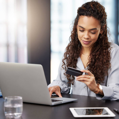 A woman online shopping on her laptop while holding her credit card.