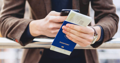A person holding a passport with a boarding pass stuck inside.