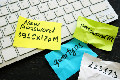 Near a white computer keyboard are several weak passwords written on sticky notes plus one with a new strong password.