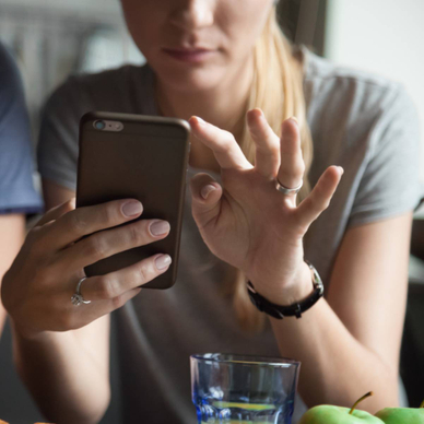 A woman holding her smartphone and scrolling through an app.