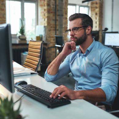 Side view of a man working on a computer in his office. 