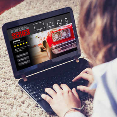 A woman hunched over laptop on floor looking at streaming app concept of Netflix